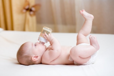 Новорожденный ребенок пьет воду из бутылочки