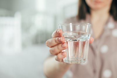 Женщина держит стакан воды