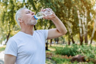 Мужчина пьет воду из пластиковой бутылки
